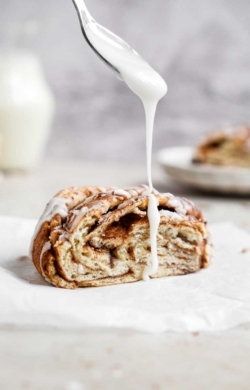 Vegan Cinnamon Roll Twist Bread being drizzled with Icing | cookingwithparita.com