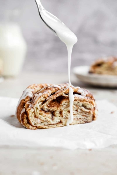 Vegan Cinnamon Roll Twist Bread being drizzled with Icing | cookingwithparita.com