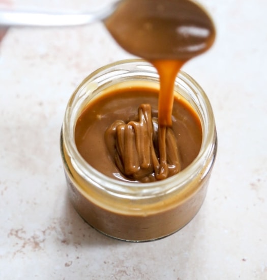 overhead image of homemade caramel sauce dripping from spoon overhead image of vegan turtle thumbprint cookies with camarel sauce | cookingwithparita.com| cookingwithparita.com