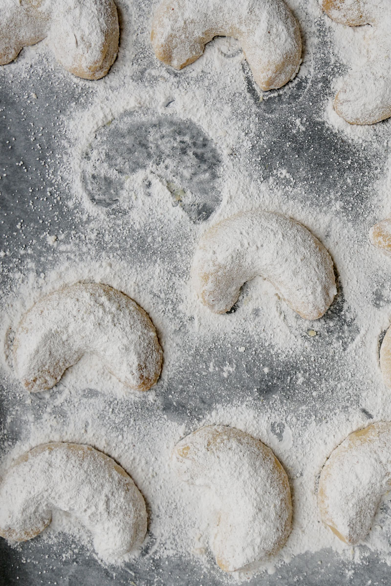 Image of Vegan Vanillekipferl (German Vanilla Crescent Cookies) dusted with icing sugar| cookingwithparita.com