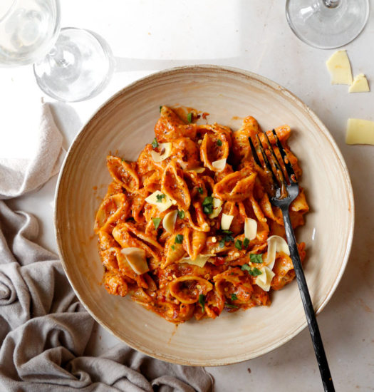 image of vegan one pot red pesto pasta bake with vegan cheese and chilli flakes on top