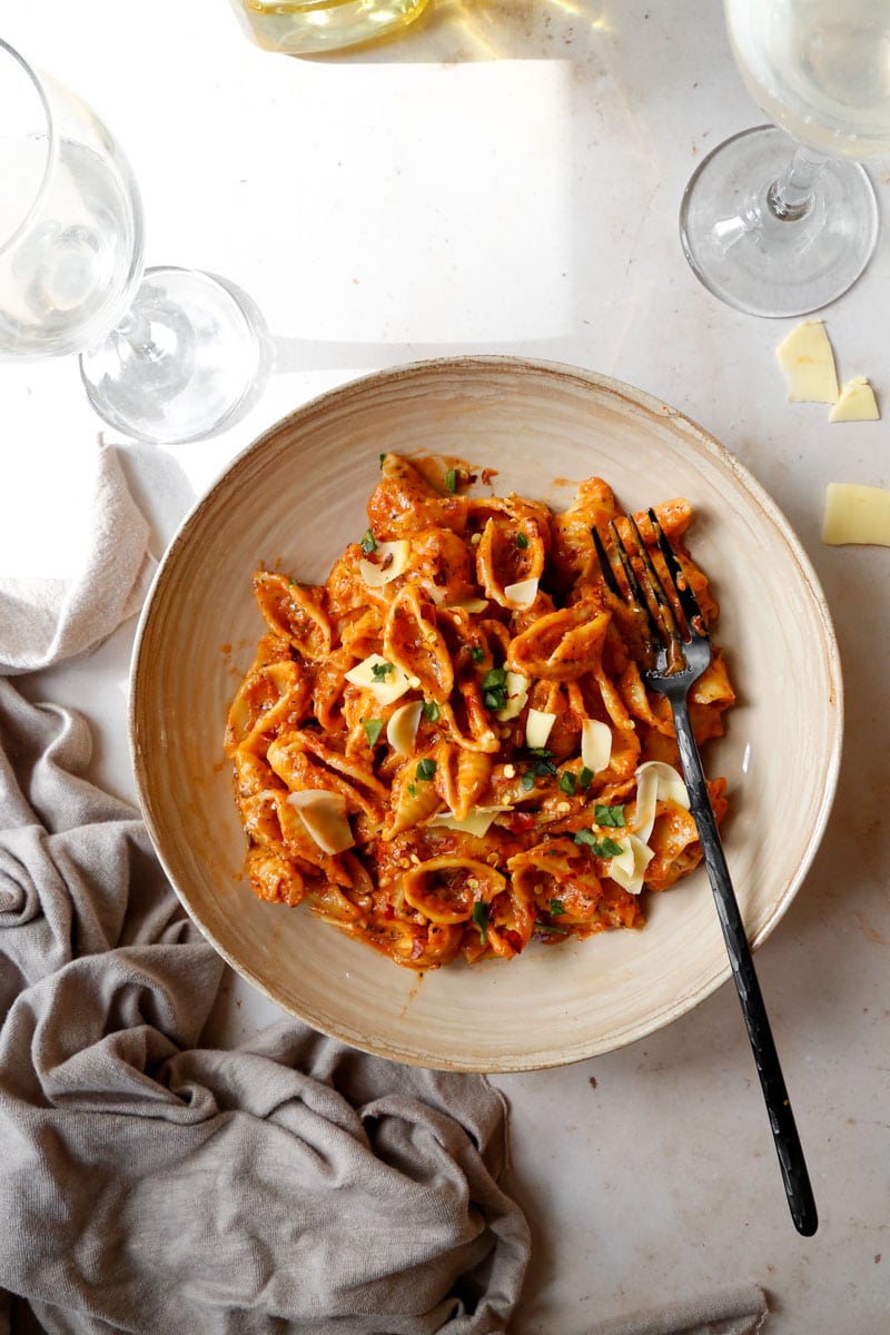 image of vegan one pot red pesto pasta bake with vegan cheese and chilli flakes on top