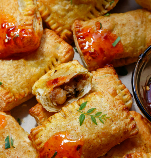Image of vegan curry puffs cut in half with sweet chilli sauce