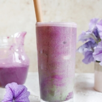 Image of iced blueberry matcha latte recipe, ready to drink with a wooden straw